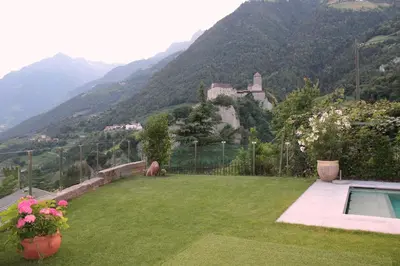 a backyard with a view of a house and mountains at Villa Falkner in Tirolo
