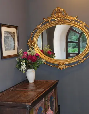 a mirror on top of a wooden table with flowers at Villa Falkner in Tirolo