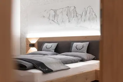 a bedroom with a bed with a drawing on the wall at Apartment Cësa Zinch in Ortisei