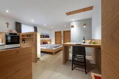 a kitchen and living room with a counter and a bed at Apartment Cësa Zinch in Ortisei
