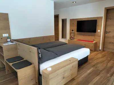 a bedroom with a large bed and a flat screen tv at Apartment Cësa Zinch in Ortisei