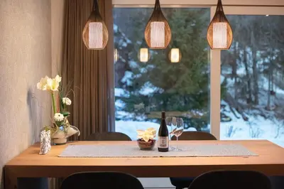 a dining room table with a bottle of wine and a window at Apartment Cësa Zinch in Ortisei