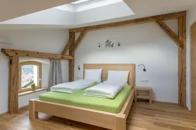 a bedroom with a wooden bed and a window at Ansitz Mairhof in Parcines
