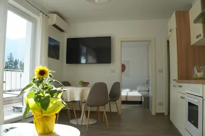 a kitchen and dining room with a table and a vase with a sunflower at Apartment Roma in Merano