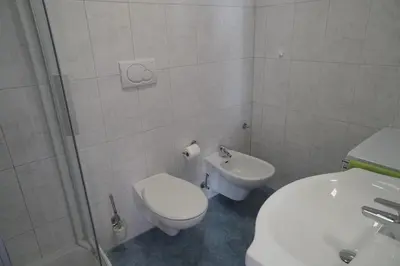 a white bathroom with a toilet and a sink at Apartment Roma in Merano