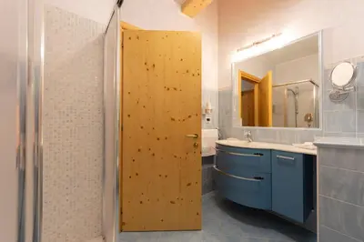 a bathroom with a wooden door and a sink at Hotel Des Alpes in Soraga