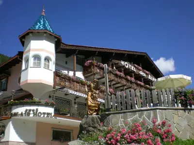 a building with a statue in front of it at Hotel Des Alpes in Soraga