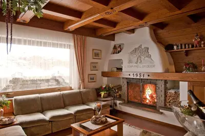 a living room with a couch and a fireplace at Hotel Des Alpes in Soraga