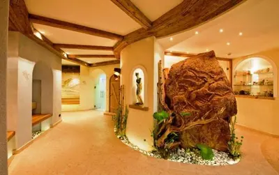 a large aquarium in a room with a large rock at Hotel Des Alpes in Soraga