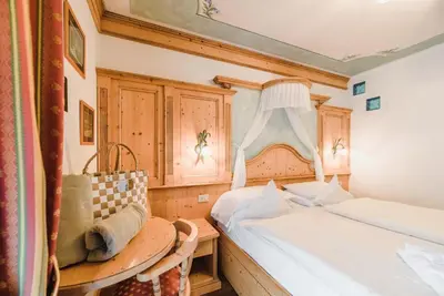 a bedroom with two beds and a table and a window at Hotel Des Alpes in Soraga