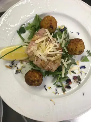 a plate of food with meatballs and a salad at Hotel Olaga in Valdaora