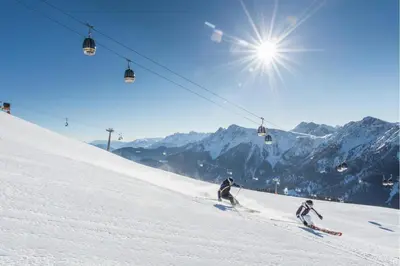 two people skiing down a snow covered ski lift at Hotel Olaga in Valdaora
