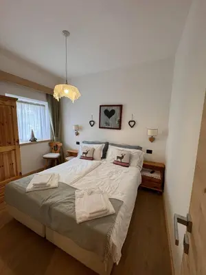 a bedroom with a large bed and a chandelier at Appartamento Continental - 8 posti letto in San Vito di Cadore
