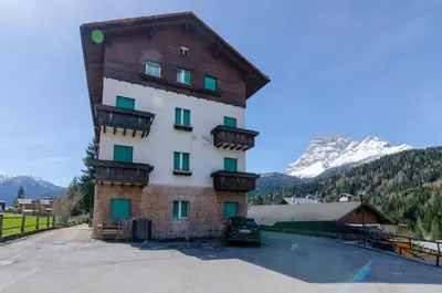 a building with balconies and a car parked in a parking lot at Appartamento Continental - 8 posti letto in San Vito di Cadore