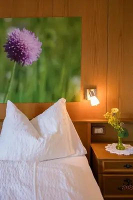 a bedroom with a bed and a vase with a purple flower at Thalerhof Tiers in Tires