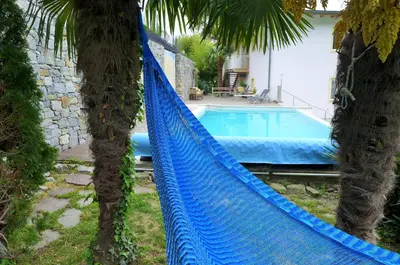 a blue hammock between two palm trees with a swimming pool at Appartement Trafoier in Tirolo