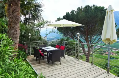 a table and chairs and an umbrella on a wooden deck at Appartement Trafoier in Tirolo