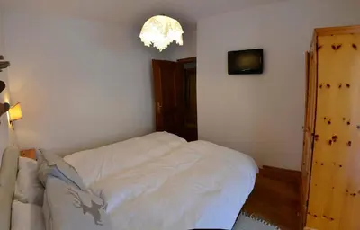 a bedroom with a white bed and a chandelier at Continental 101- 4 beds in San Vito di Cadore
