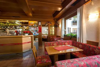 a restaurant with red chairs and a table and a bar at Hotel Garnì Ai Serrai in Rocca Pietore