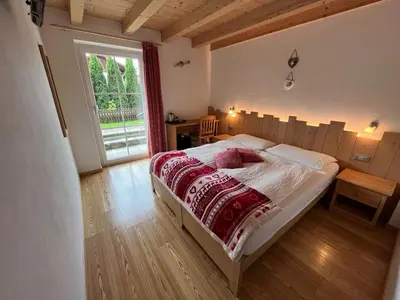 a bedroom with a bed and a large window at Affittacamere Famiglia Ceschini in Tesero