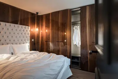 a bedroom with a white bed and a wooden wall at Messnerhaus Suite in Siusi