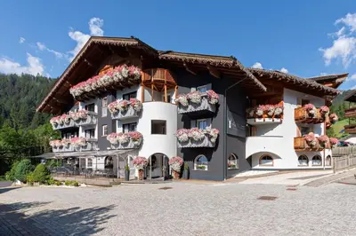 a black and white building with flower boxes at Hotel Madonnina Resort And Wellness in Soraga