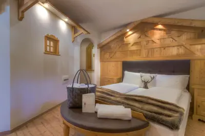 a bedroom with a large bed and a table at Hotel Madonnina Resort And Wellness in Soraga