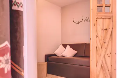 a living room with a couch and a wooden door at Hotel Madonnina Resort And Wellness in Soraga