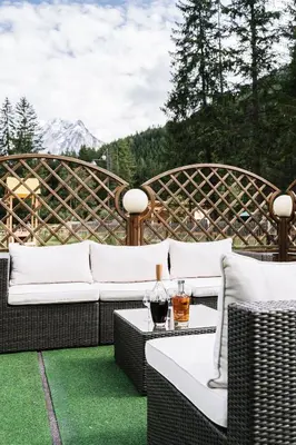 a patio with white couches and a table with a drink at Chalet Pineta relax location in Canazei