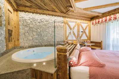 a bathroom with a tub and a bed in a room at Chalet Pineta relax location in Canazei
