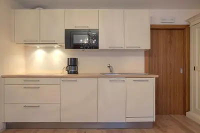 a kitchen with white cabinets and a sink at Ciasa La Rô in San Cassiano