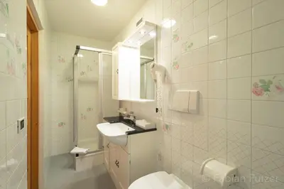 a white bathroom with a sink and a toilet at Ciasa La Rô in San Cassiano
