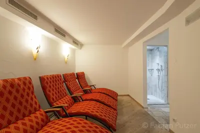 a waiting room with red chairs and a shower at Ciasa La Rô in San Cassiano