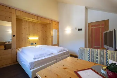 a bedroom with a bed and a table and a tv at Ciasa La Rô in San Cassiano
