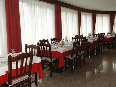 a dining room with tables and chairs with red curtains at Albergo Dolomiti in Fiera di Primiero