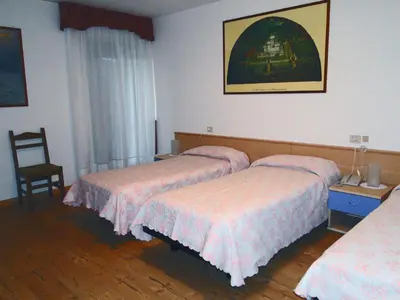 a hotel room with two beds and a chair at Albergo Dolomiti in Fiera di Primiero