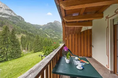 a green table on a balcony with a view of mountains at Aparthotel Princess in Canazei