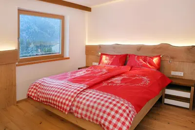 a bedroom with a bed with red sheets and a window at Apartment Kristyn in Ortisei