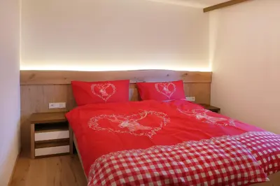 a bedroom with a red bed with two red pillows at Apartment Kristyn in Ortisei