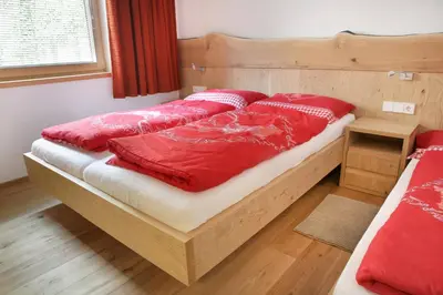 a bed with red sheets and red pillows on it at Apartment Kristyn in Ortisei