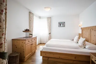 a bedroom with a large bed and a window at Piculin Alpin Apartments in San Martino in Badia