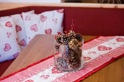 a glass vase with pine cones in it on a table at Piculin Alpin Apartments in San Martino in Badia
