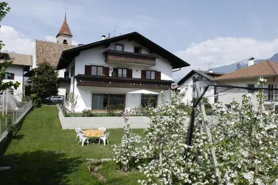 a house with a yard with a table and white flowers at Haus Sankt Peter in Lana