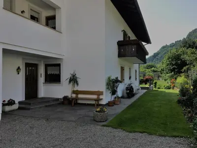 a white house with a bench next to a yard at Haus Sankt Peter in Lana