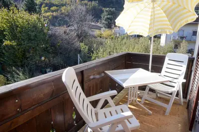 a table and chairs on a balcony with an umbrella at Haus Sankt Peter in Lana