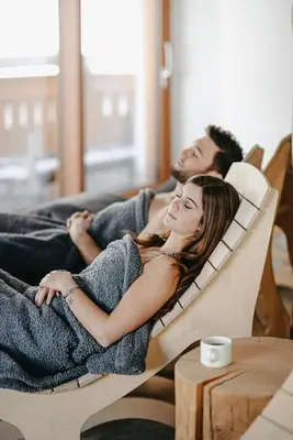 a man and a woman laying on a couch at Hotel Aurai in Telve