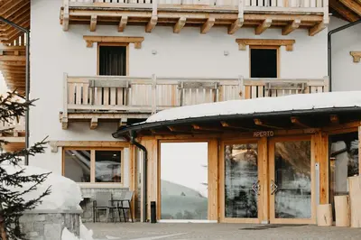 a building with a balcony with snow on it at Hotel Aurai in Telve