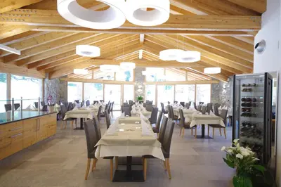 a dining room with tables and chairs and wooden ceilings at Hotel Aurai in Telve
