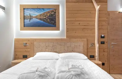 a bedroom with a white bed with a picture on the wall at Hotel Aurai in Telve