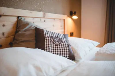 a bed with white pillows and a wooden headboard at Obergruberhof in Chiusa